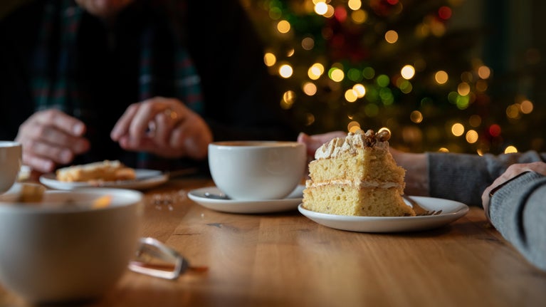 Cake and hot drinks with a Christmas tree in background